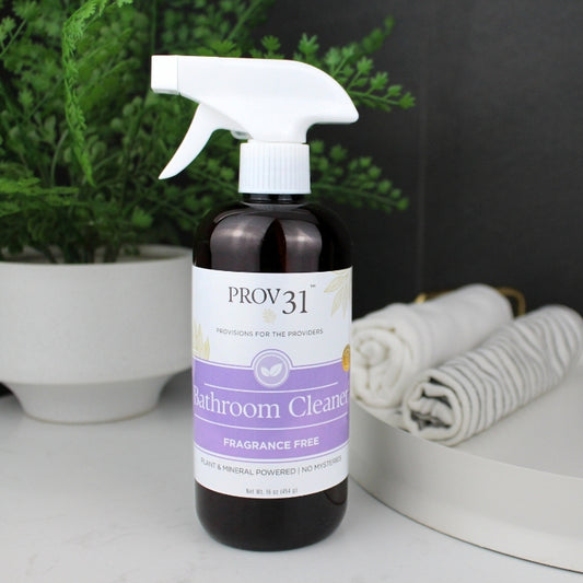 Bottle of Prov 31 Bathroom Cleaner on a surface with a plant and towels in the background
