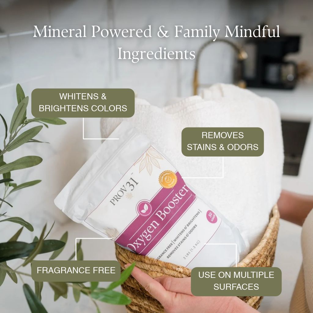 A packaged product labeled Prov 31 Oxygen Booster sits in a woven basket with folded white towels and green leaves in a kitchen setting. Text overlays describe benefits such as fabric whitening, stain removal, fragrance-free use, and multi-surface applicability.