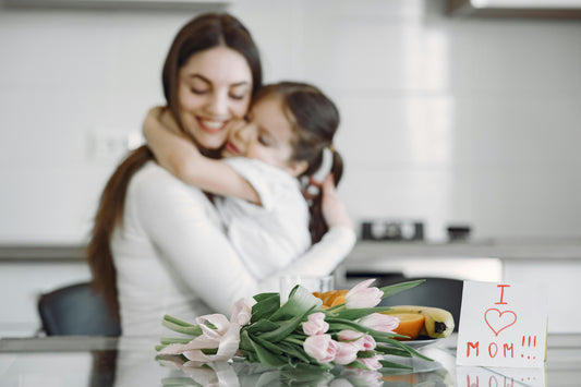 Child and mother hugging while tulips and a card sit on countertop.
