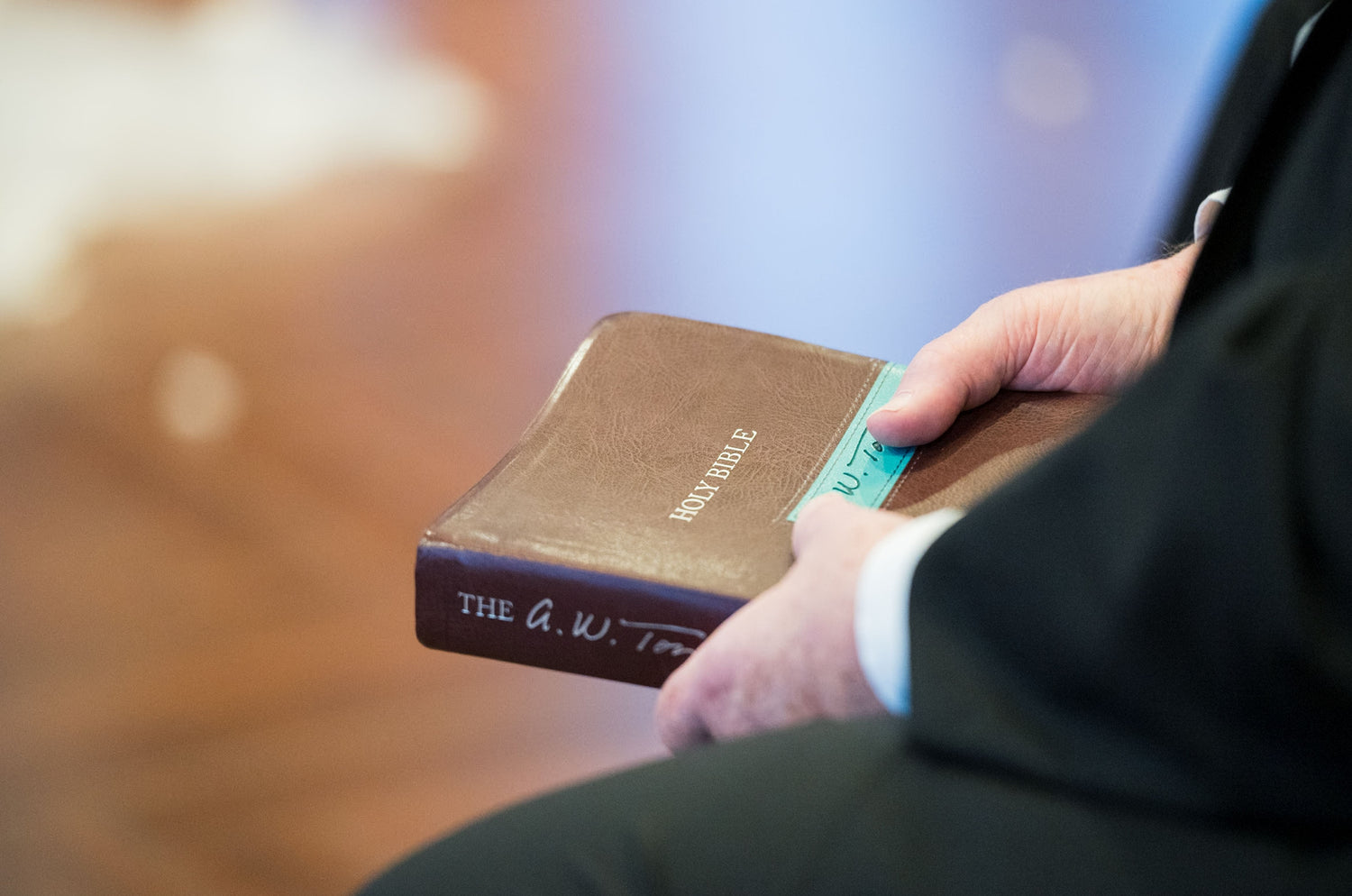 Person holding a brown Bible with a blurred background