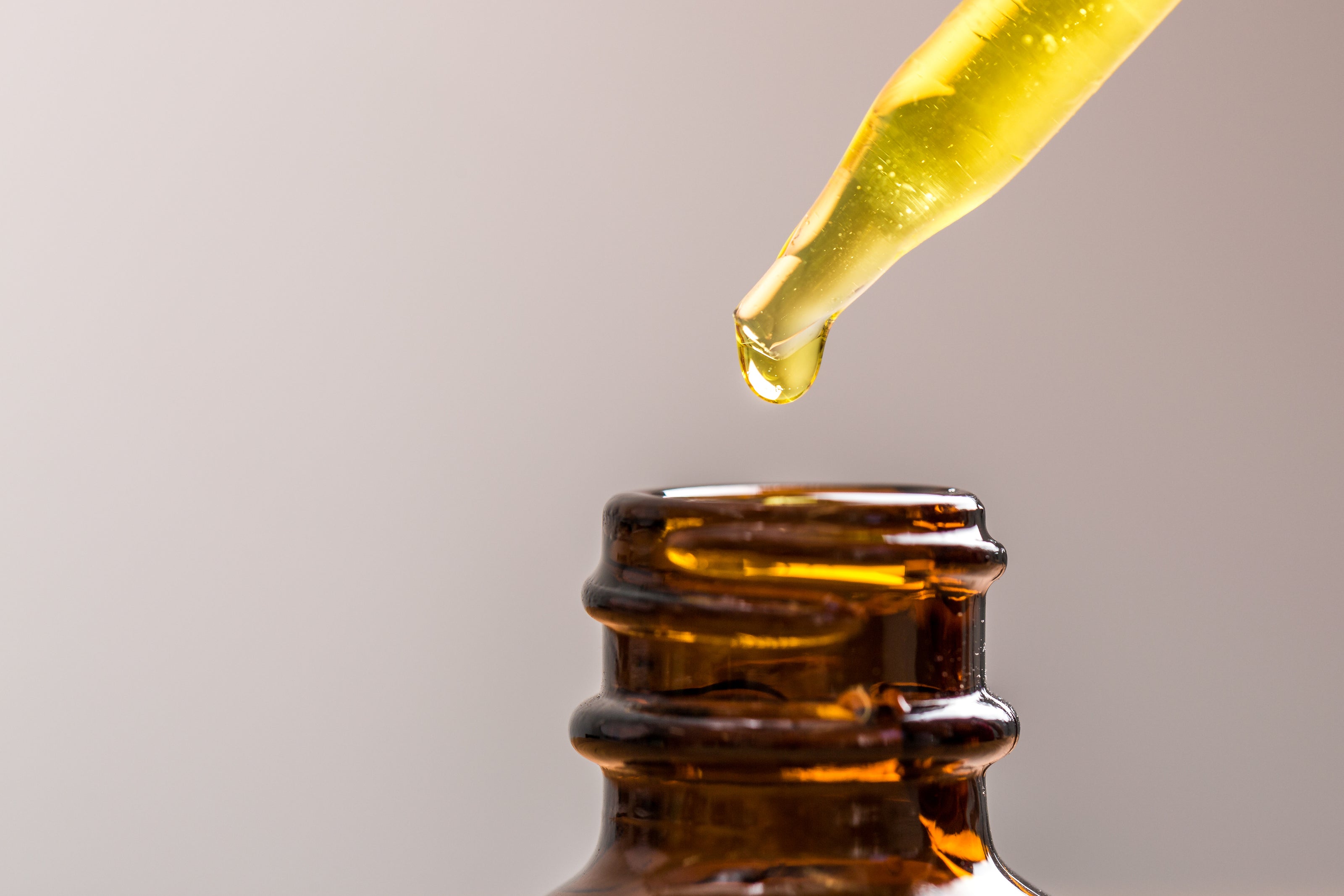 close up of oil dripping into a bottle.