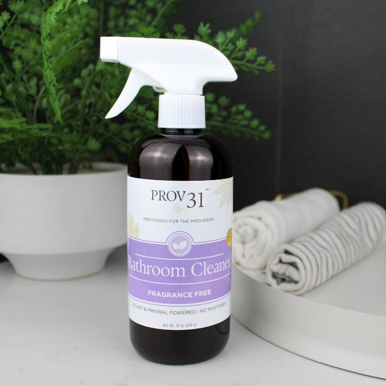 Bottle of Prov 31 Bathroom Cleaner on a surface with a plant and towels in the background