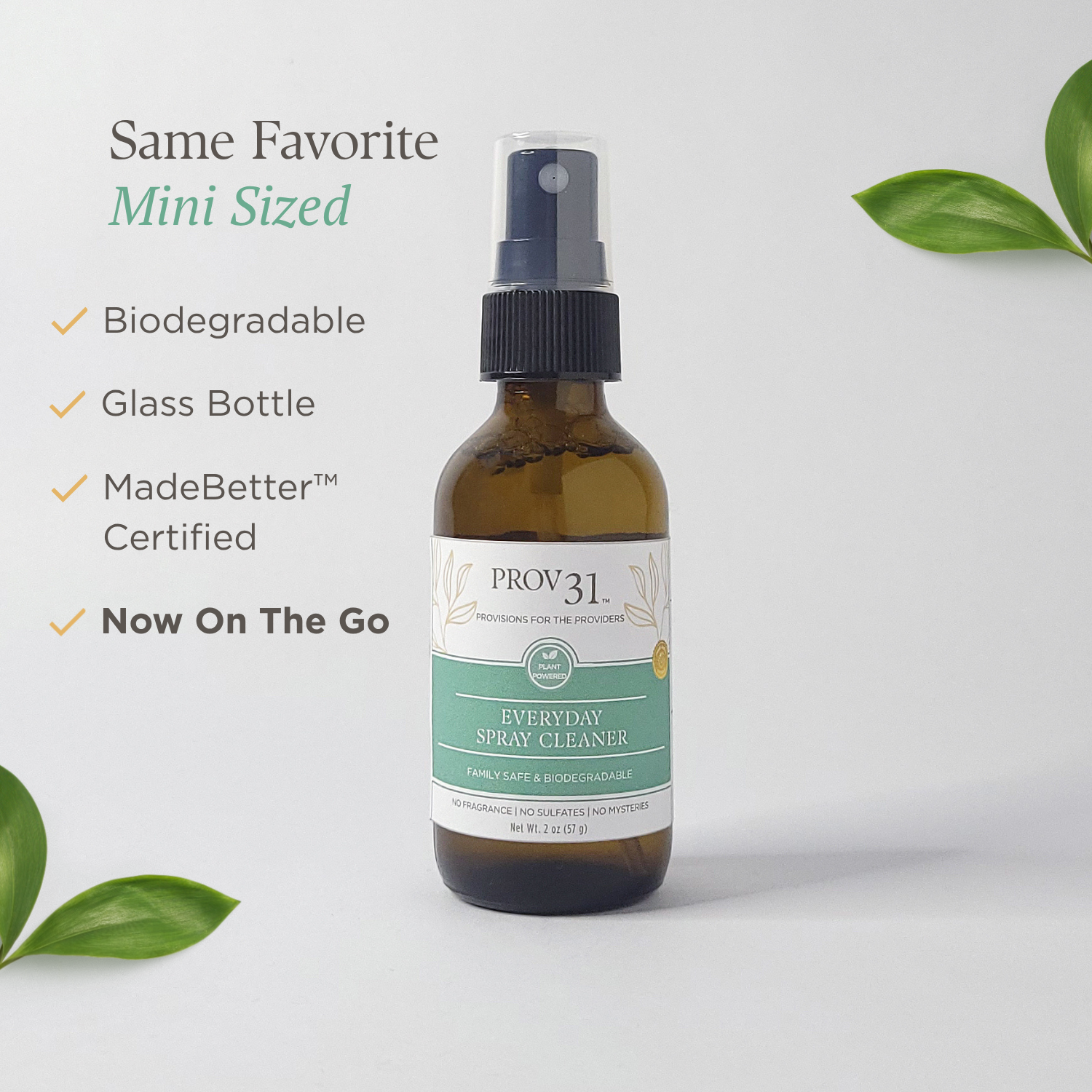 Glass bottle of Prov 31 home Everyday Spray Cleaner with green leaves on a light gray background