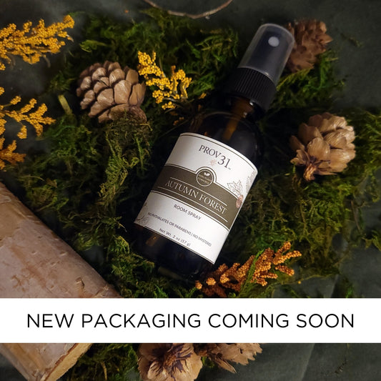 Bottle of Prov 31 Autumn Forest essential oil room spray on a decorative background with moss, pine cones, and flowers.