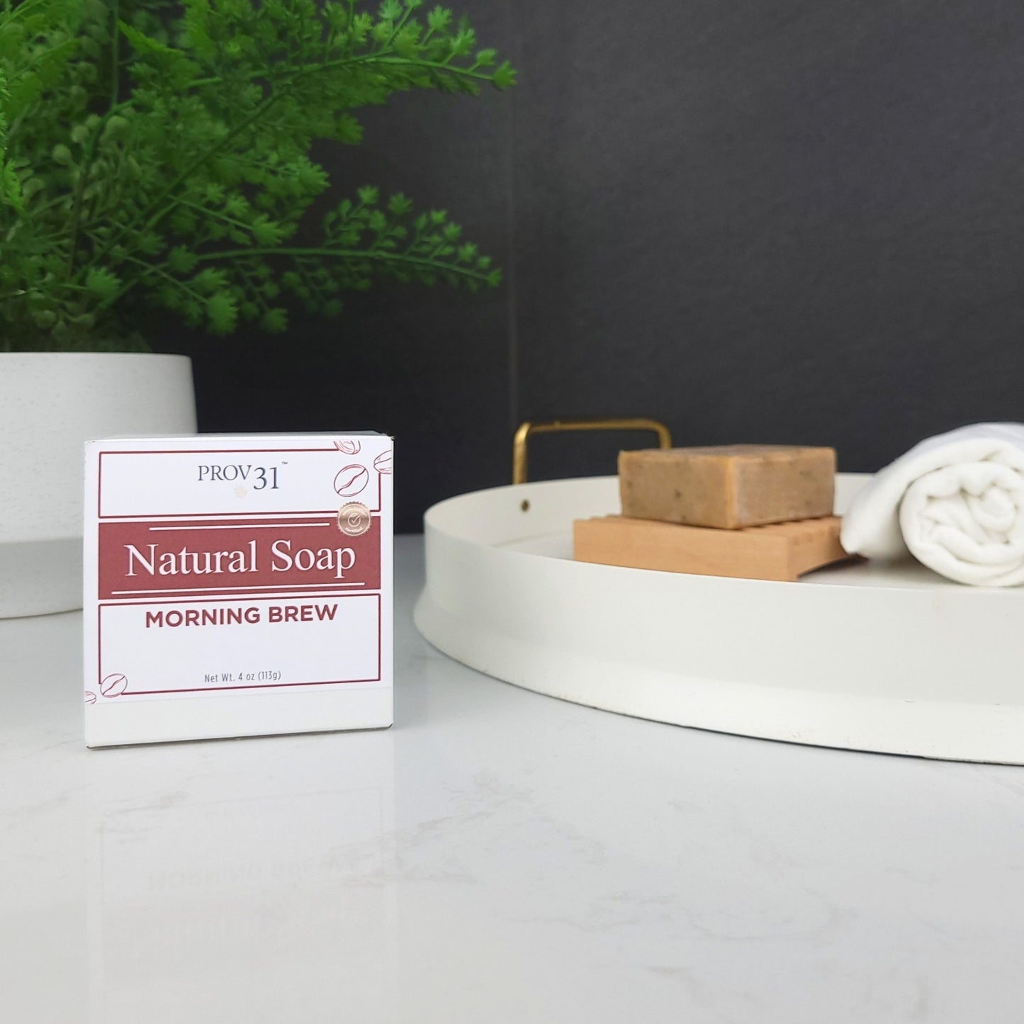 Box of  Prov 31 Coffee Scented Natural Soap on a bathroom counter with soap bars and towels.