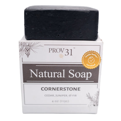 A bar of PROV 31 Natural Soap in the Cornerstone scent, made with charcoal, shown as a black rectangular bar resting on its white and gray cardboard packaging box against a white background.