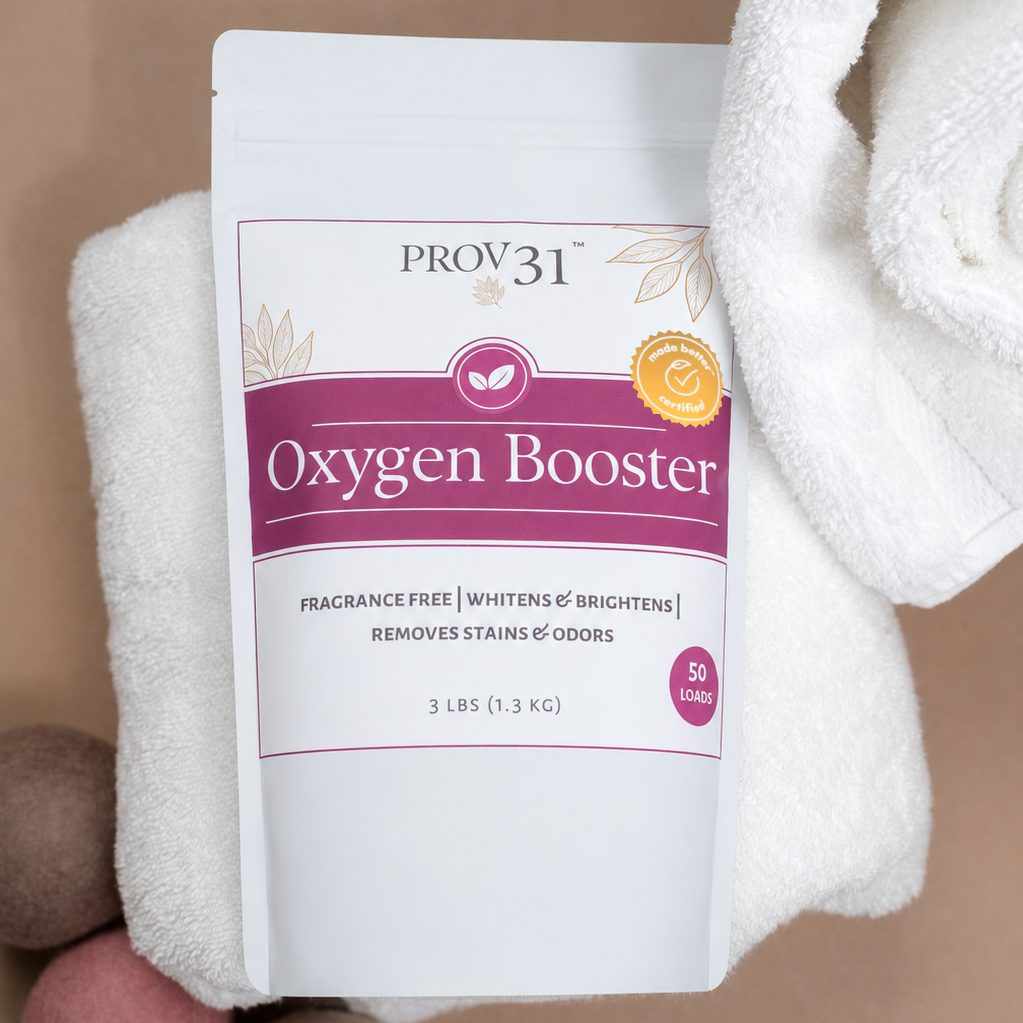 A white stand-up pouch labeled PROV31 Oxygen Booster, styled on folded white towels with wool balls against a warm beige background.